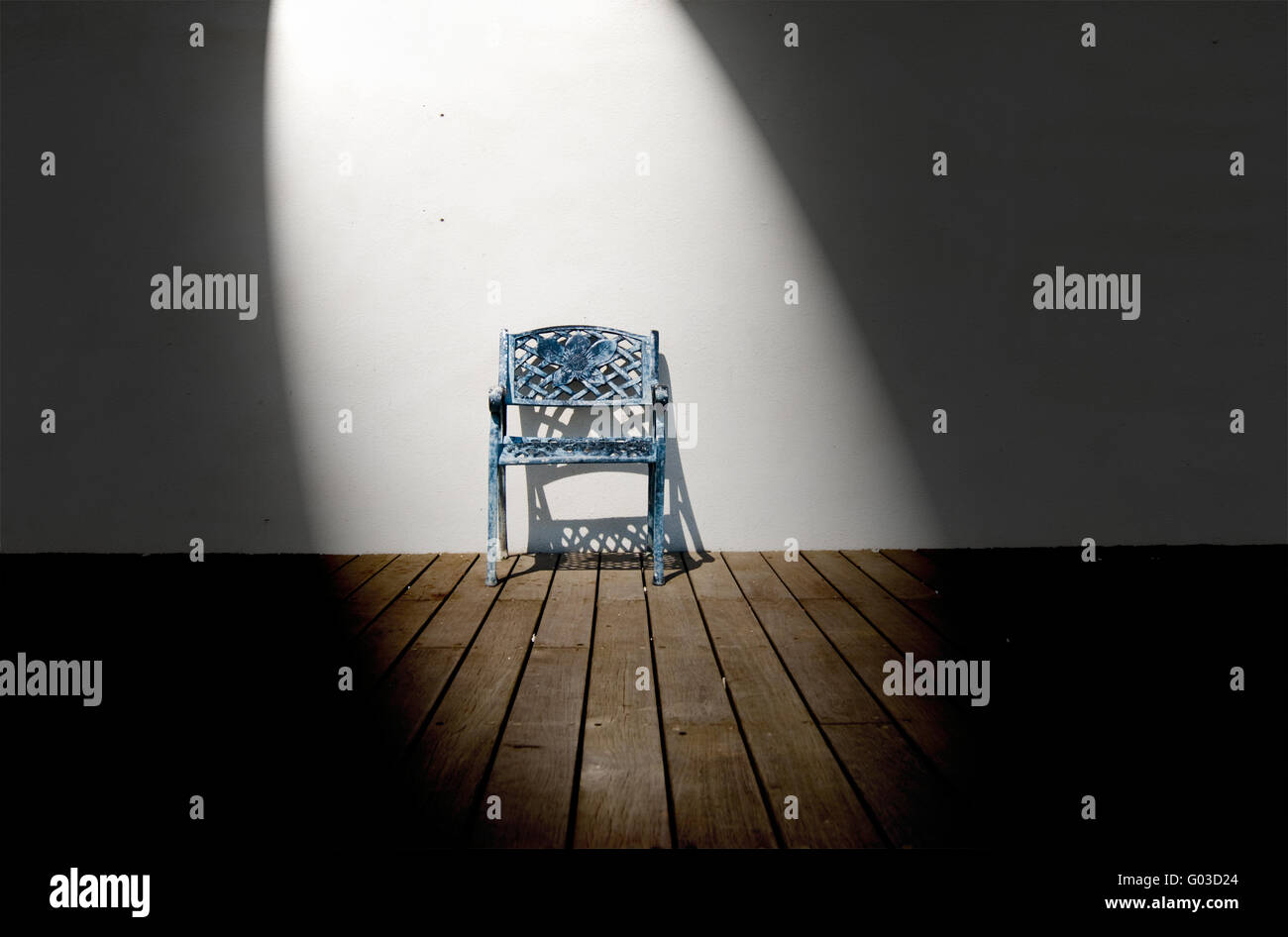 Spotlight on single iron chair on wooden floor Stock Photo