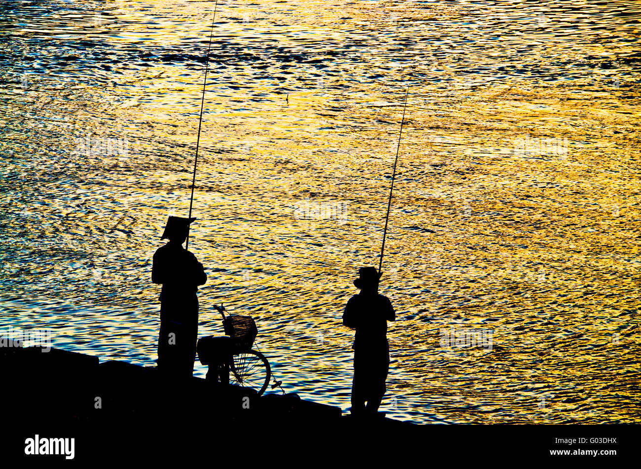 Fisherman silhouette on shoreline in sunset light Stock Photo - Alamy