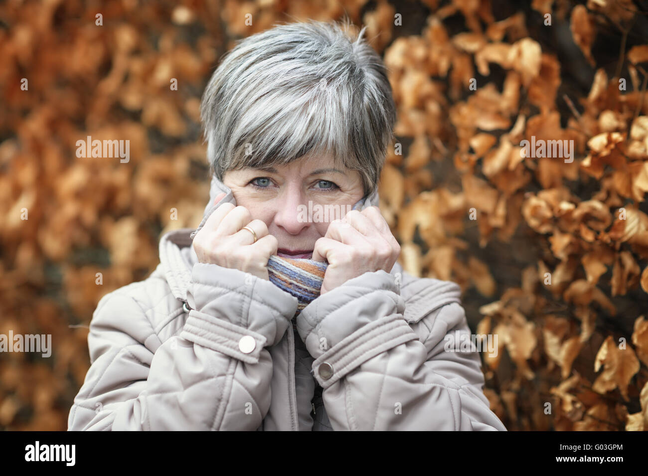 Shivering woman pulls up the collar of her coat Stock Photo