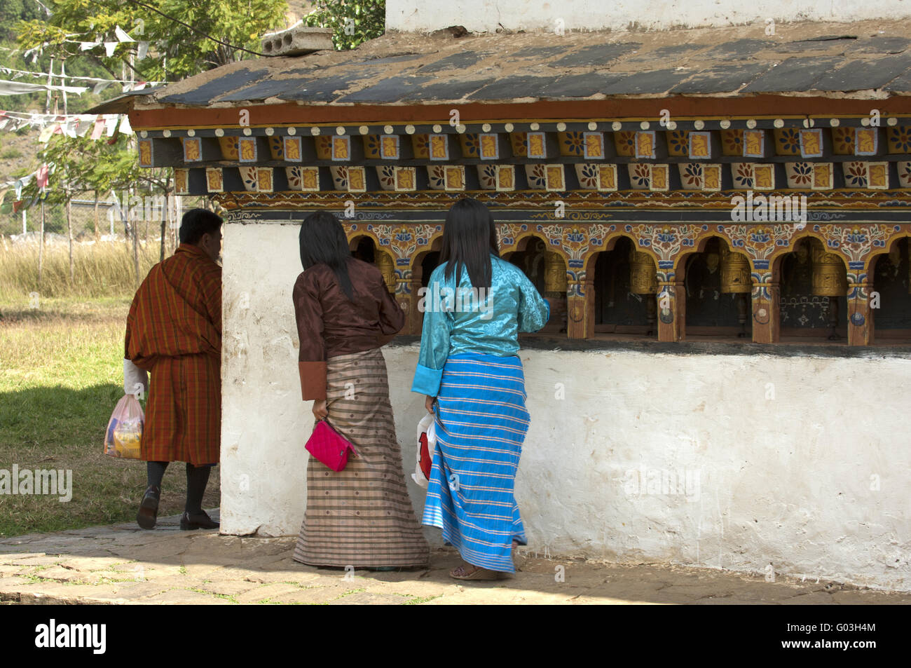 Young Bhutanese turning the prayer mills, Bhutan Stock Photo