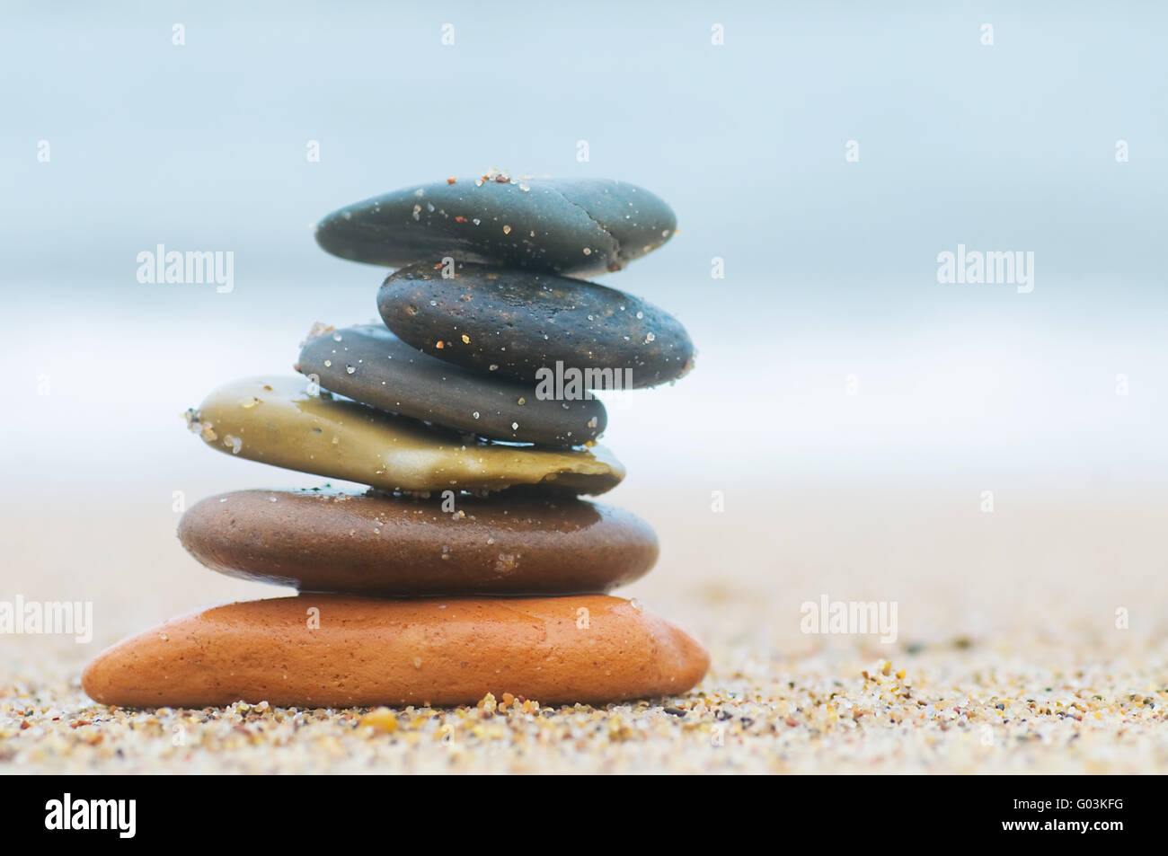Stack of beach stones on sand. Ocean in the background Stock Photo