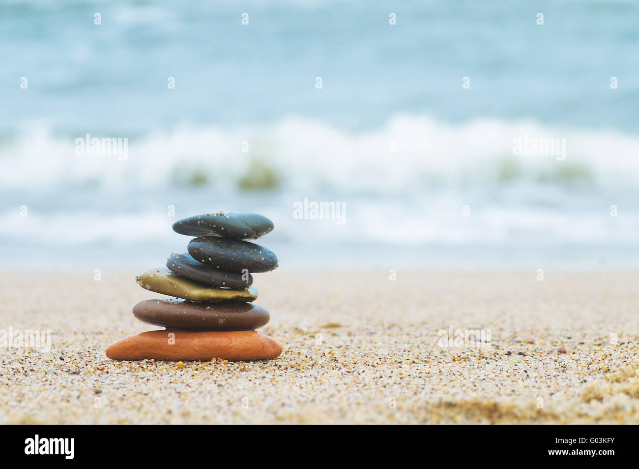 Stack of beach stones on sand. Ocean in the background Stock Photo