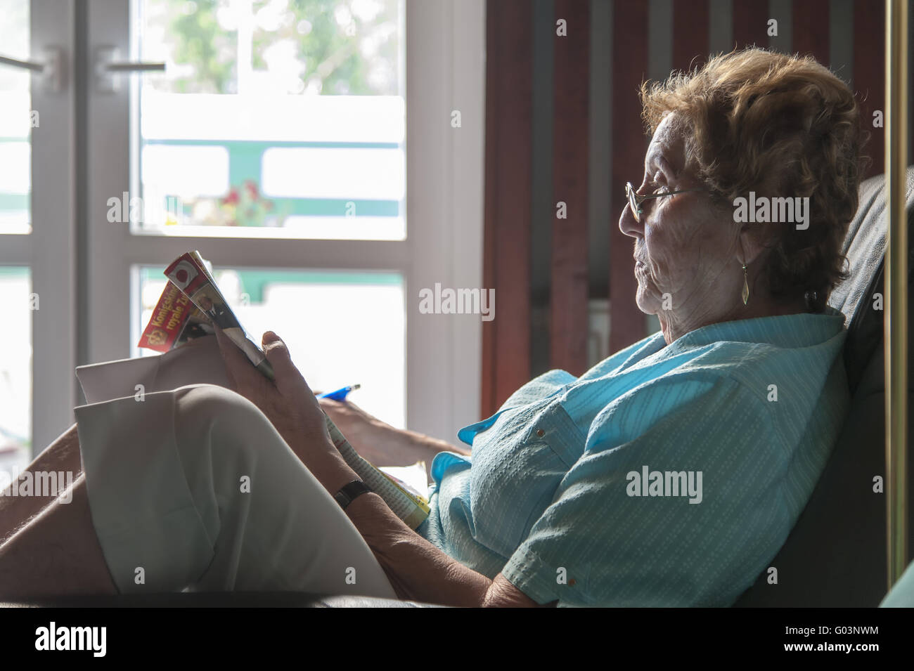 Elderly woman sitting in an armchair and reading a Stock Photo