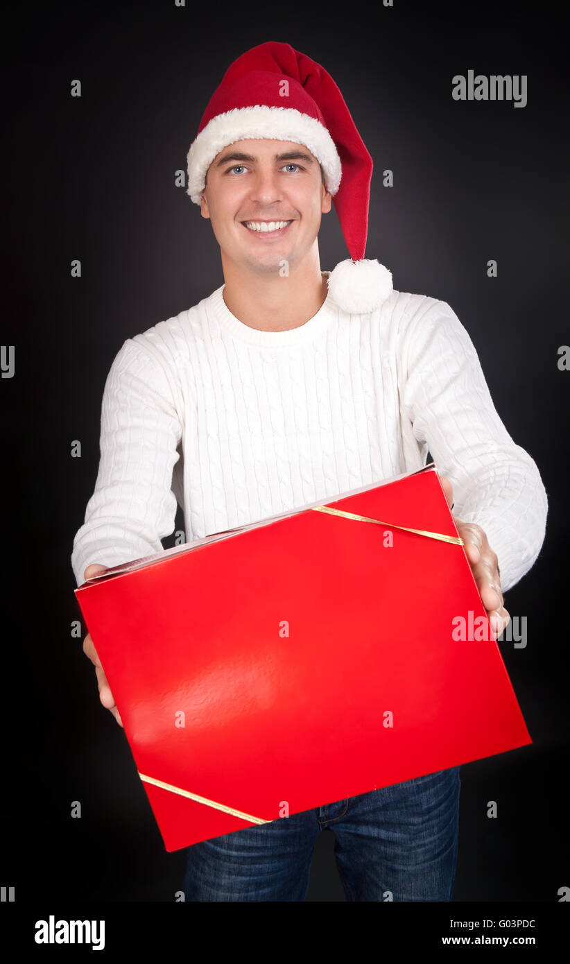 Smiling man in Santa hat gives a red box in the studio Stock Photo - Alamy