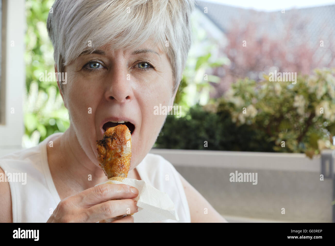 Woman biting into a freshly grilled chicken thighs Stock Photo Alamy