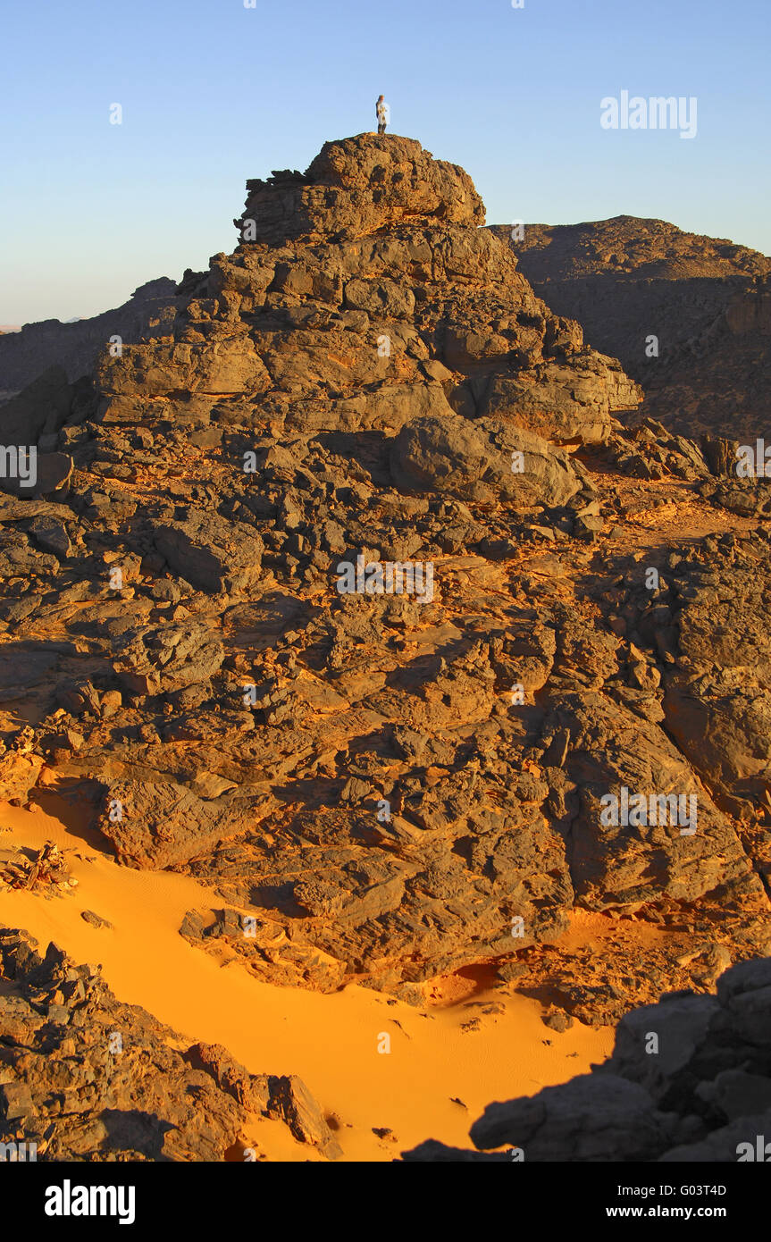 person standing on an eroded rocky hill, Sahara Stock Photo