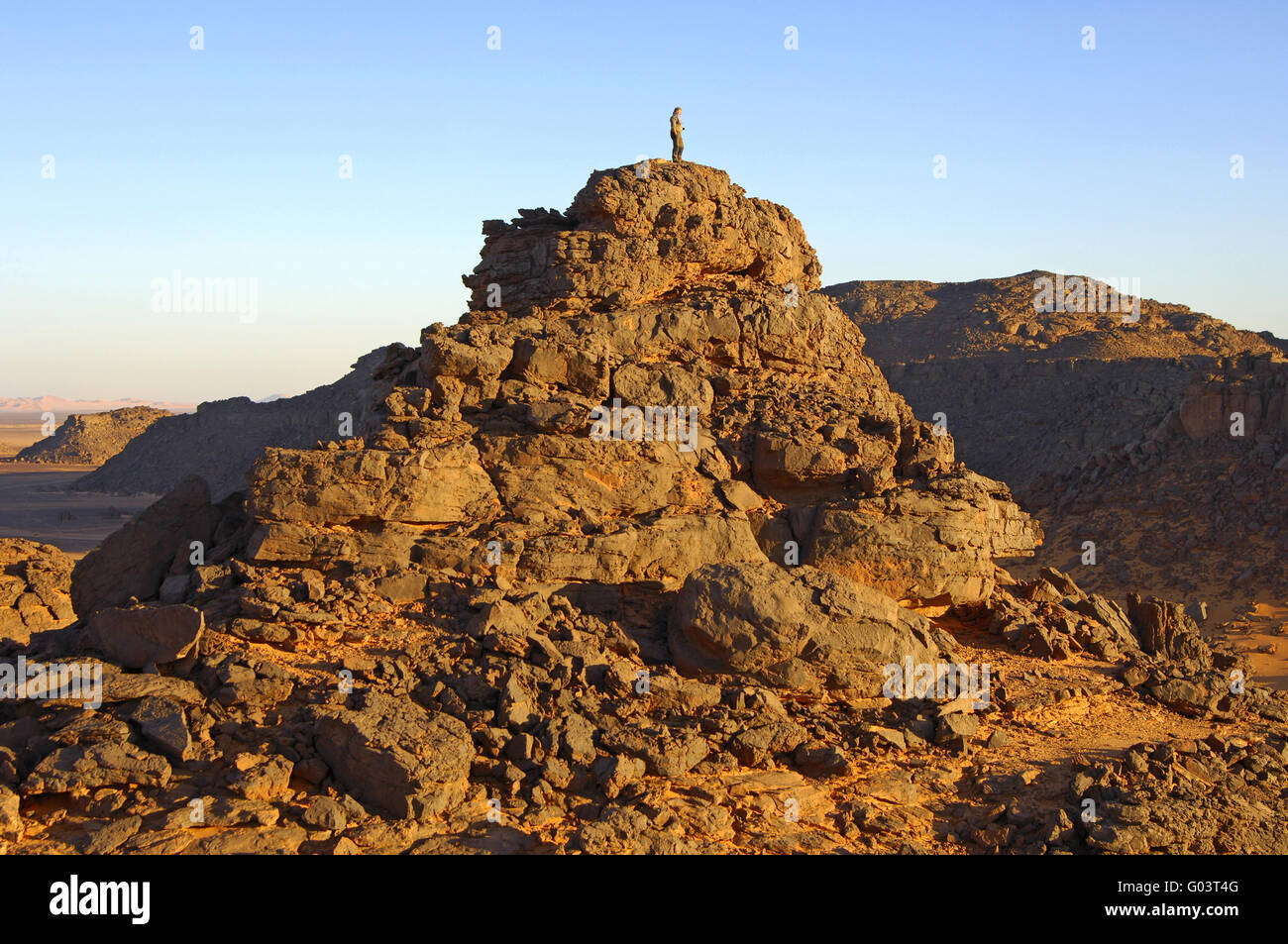 A person standing on an eroded rock hill, Sahara Stock Photo