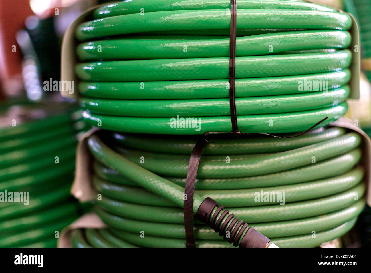 Green garden hoses coiled up and stacked on one another with shallow