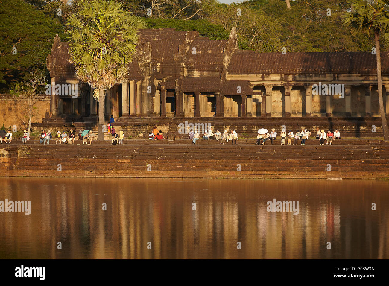 Tourists relaxing by moat around Angkor Wat (12th century Khmer temple), Angkor World Heritage Site, Siem Reap, Cambodia Stock Photo