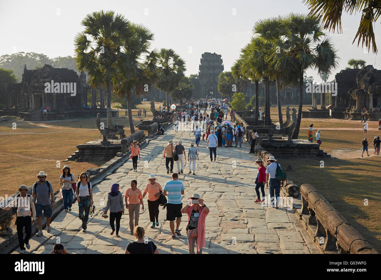 Tourists on ancient sandstone causeway to Angkor Wat (12th century