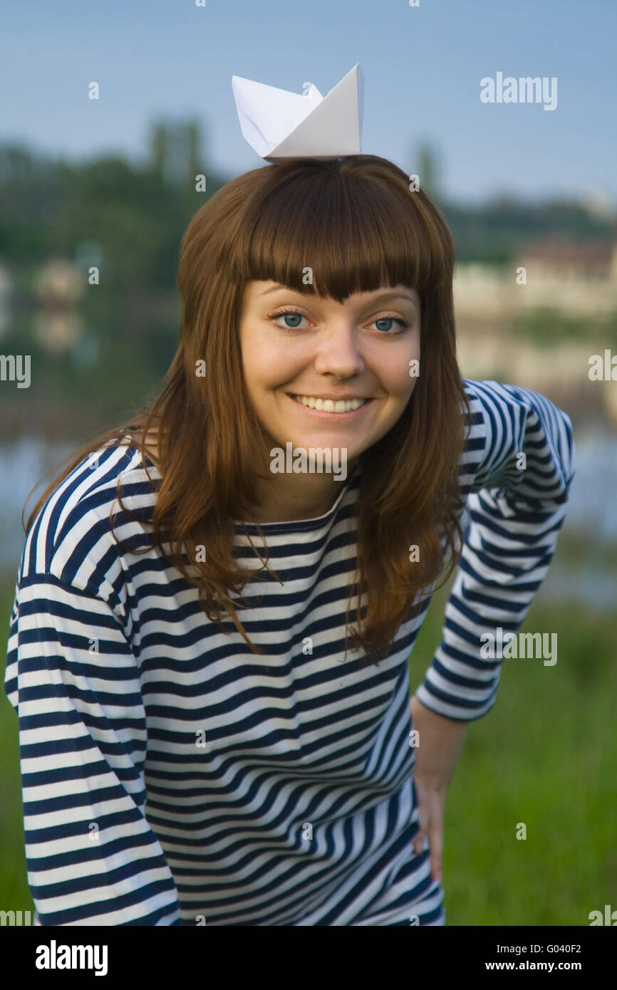 Young woman in stripped t-short with paper ship on her head Stock Photo