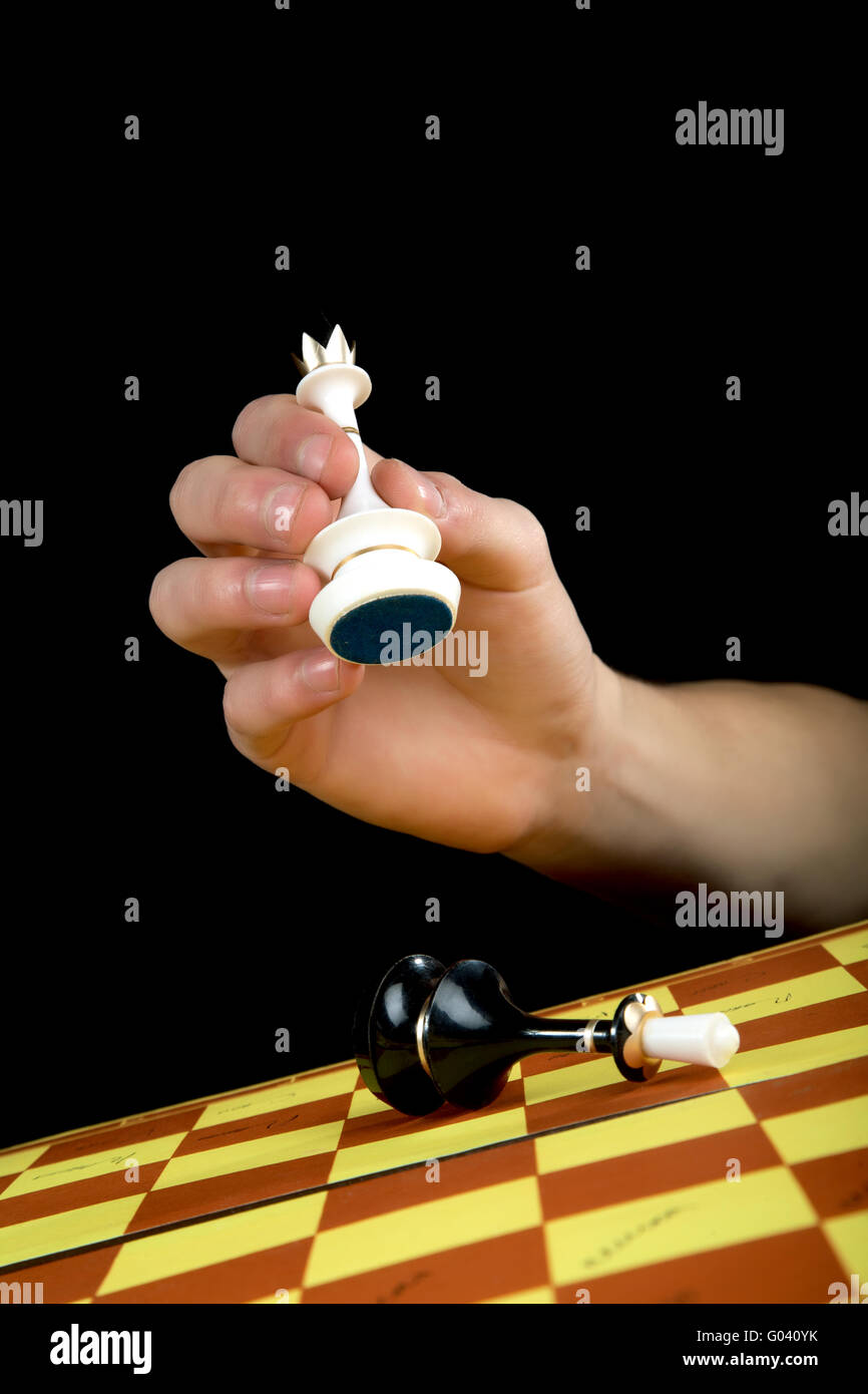 The man's hand with a queen gives checkmate to  king Stock Photo