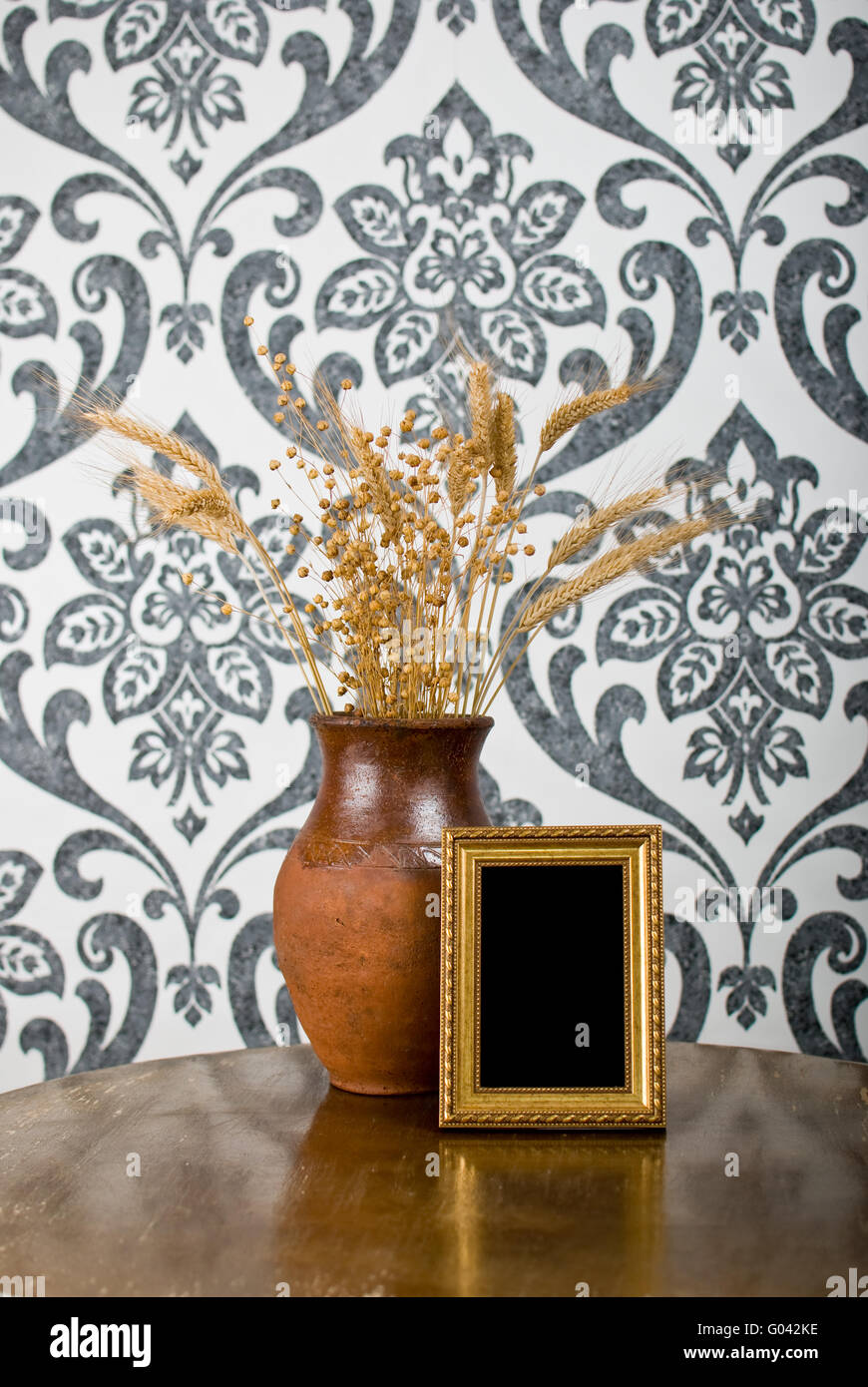 Golden photo frame and jug with wheat and flax on vintage table Stock Photo