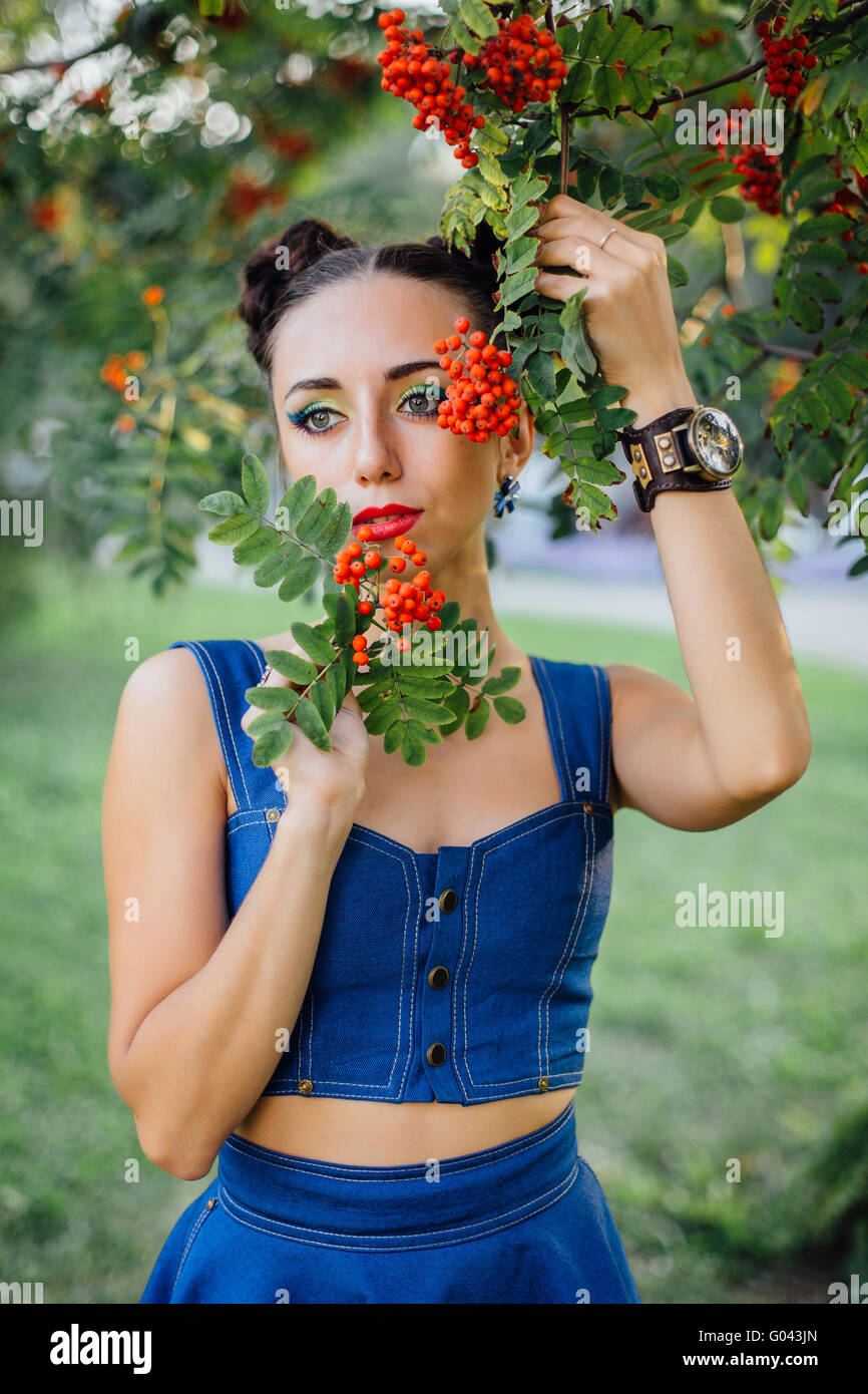 Beautiful young woman with bright make up under the rowan tree with