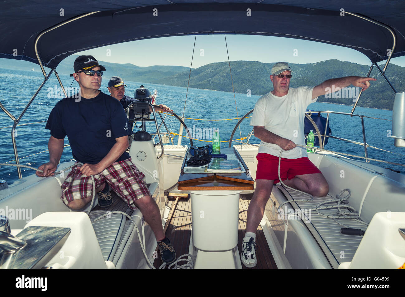 3 man crew at the stern of a sailing their yacht o Stock Photo