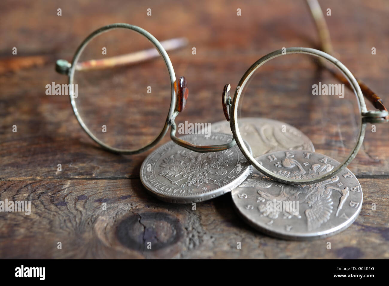 Three ancient Russian silver coins near spectacles on wooden background ...