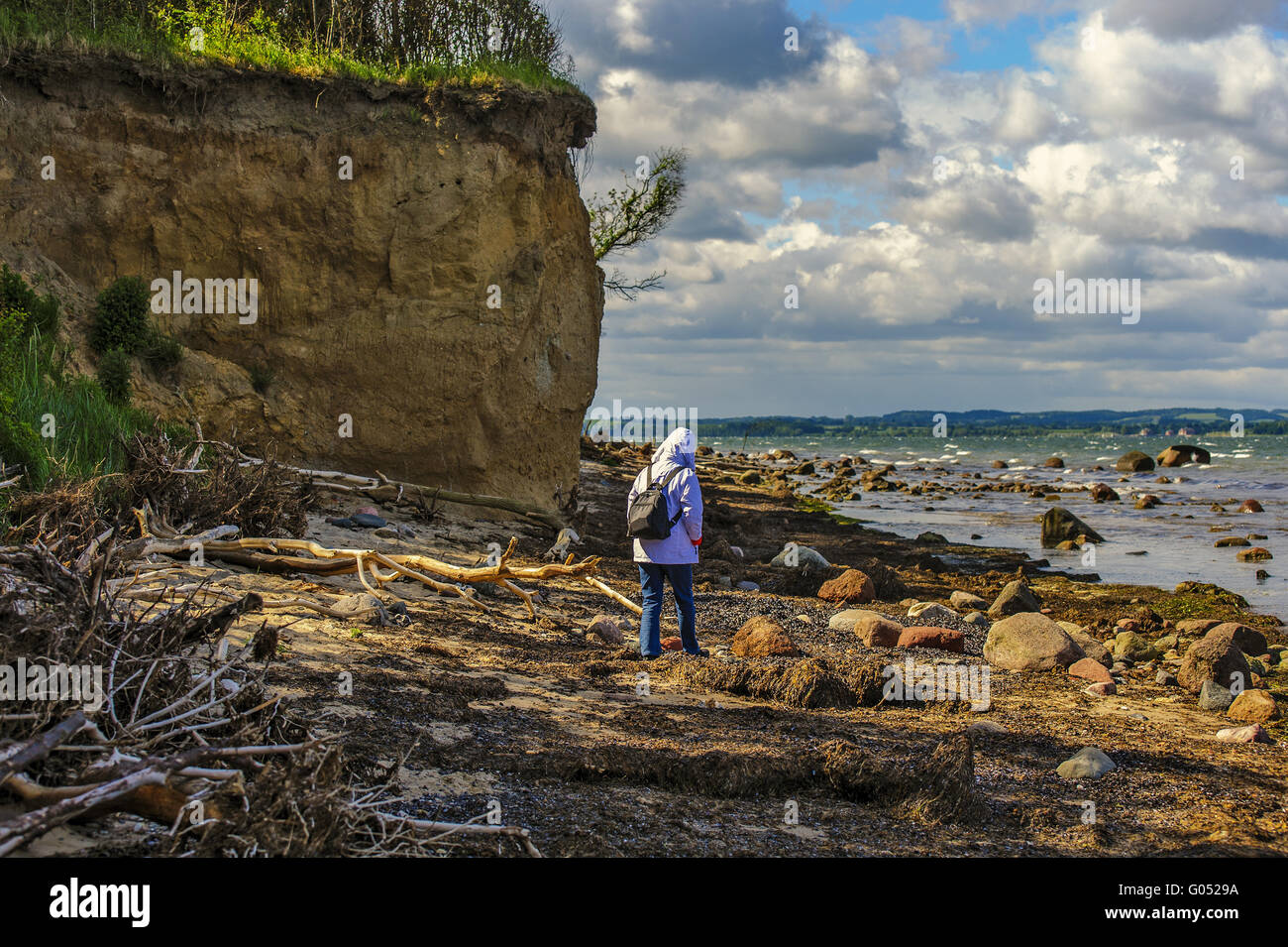 woman wandering on the beach below the cliffs Stock Photo