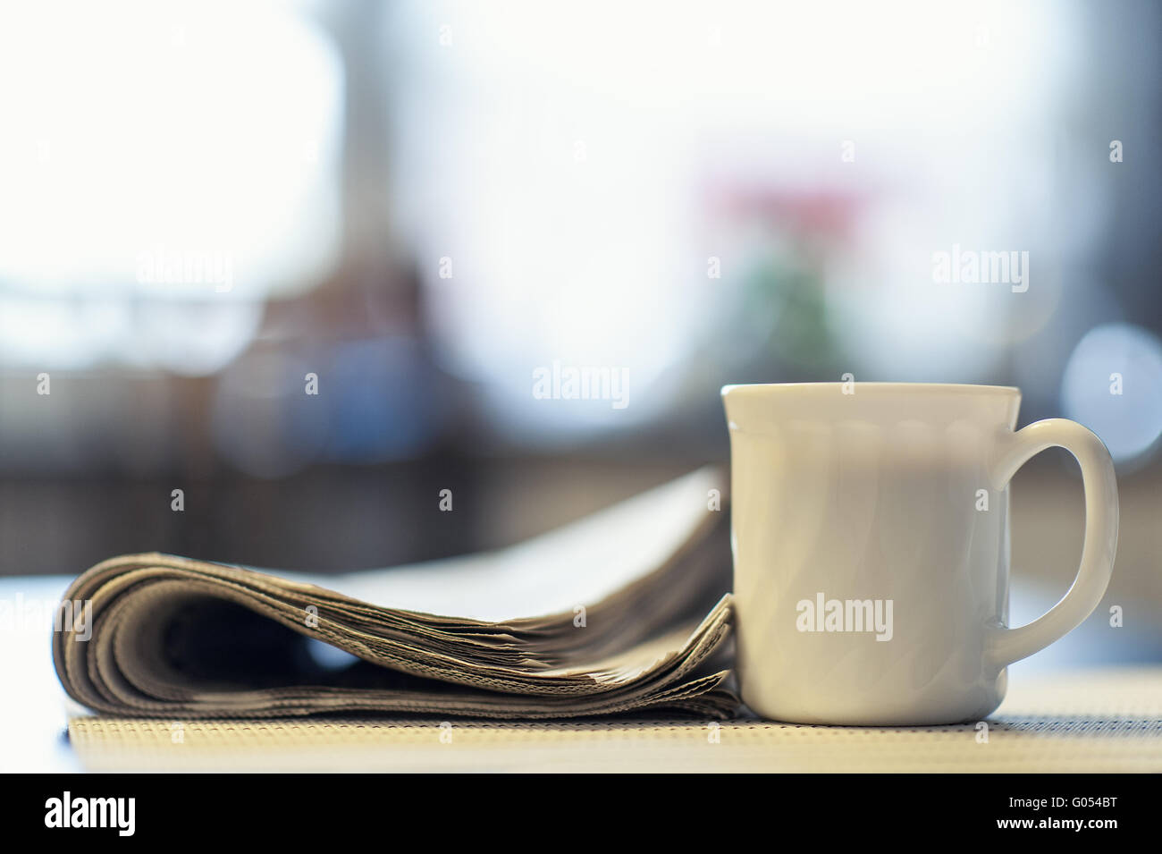 Cup of coffee and newspaper on the kitchen table Stock Photo