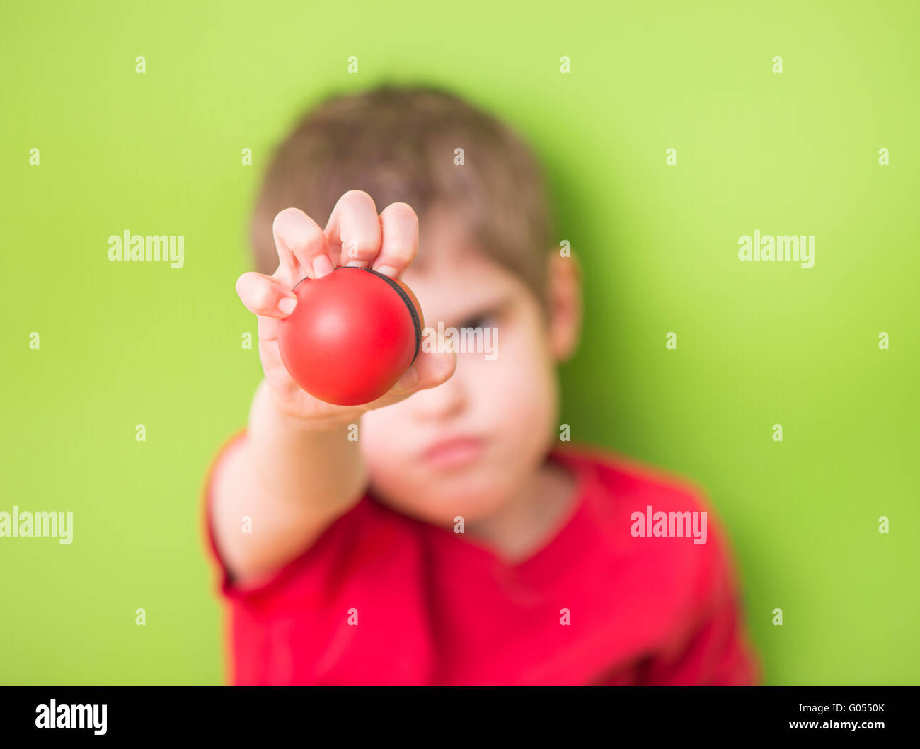 Child holding and squeezing red stress ball with hand. Concept of childhood anxiety, frustration and anger. Also a symbol of bei Stock Photo