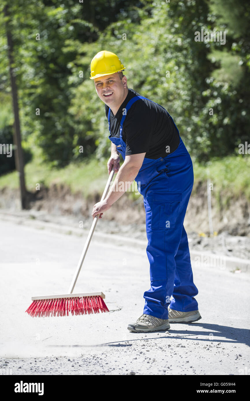 Construction worker cleans the site with a broom Stock Photo