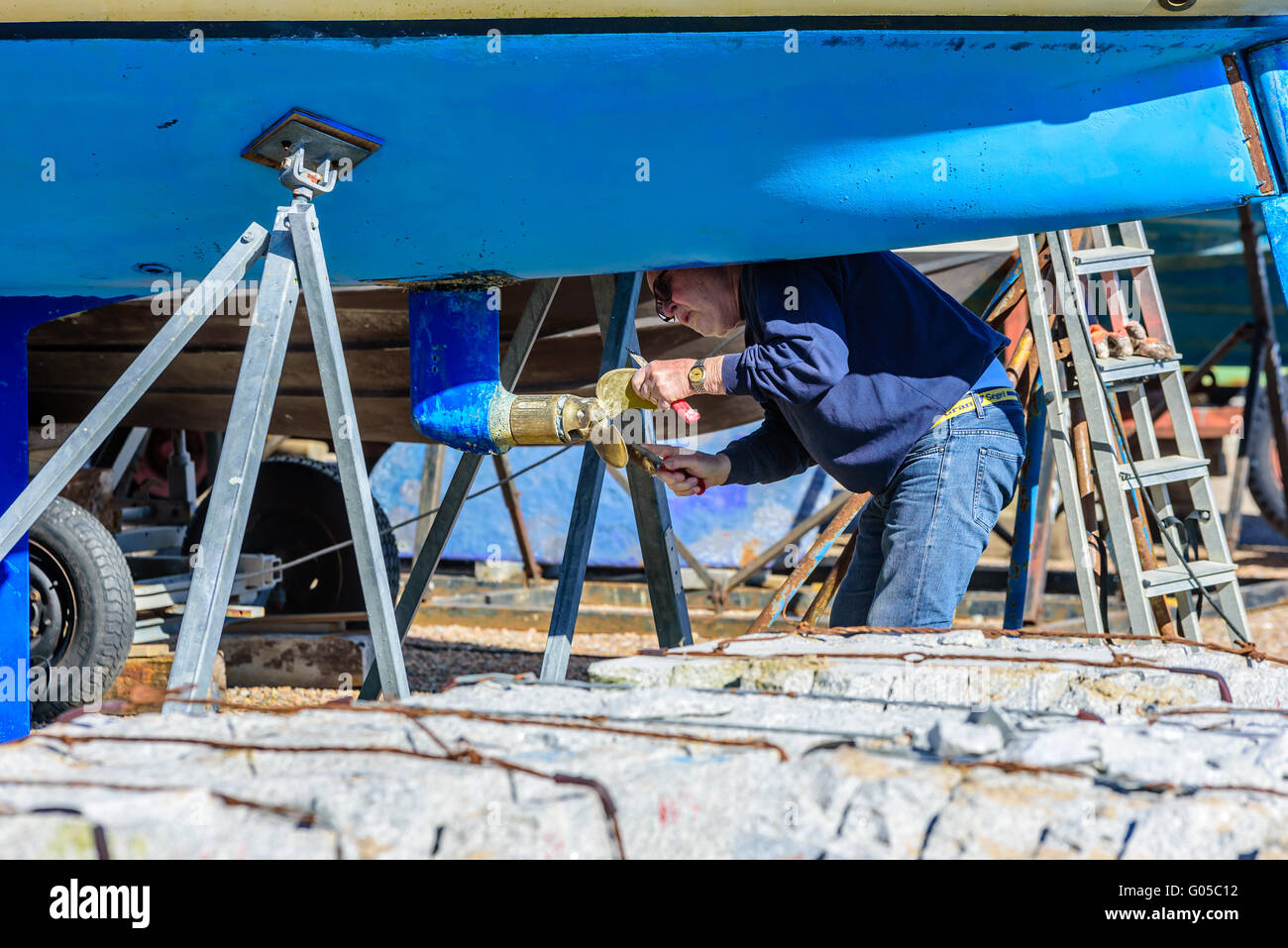 Falsterbo, Sweden - April 11, 2016: Senior adult man doing some maintenance on a boat propeller before it is time to launch the Stock Photo