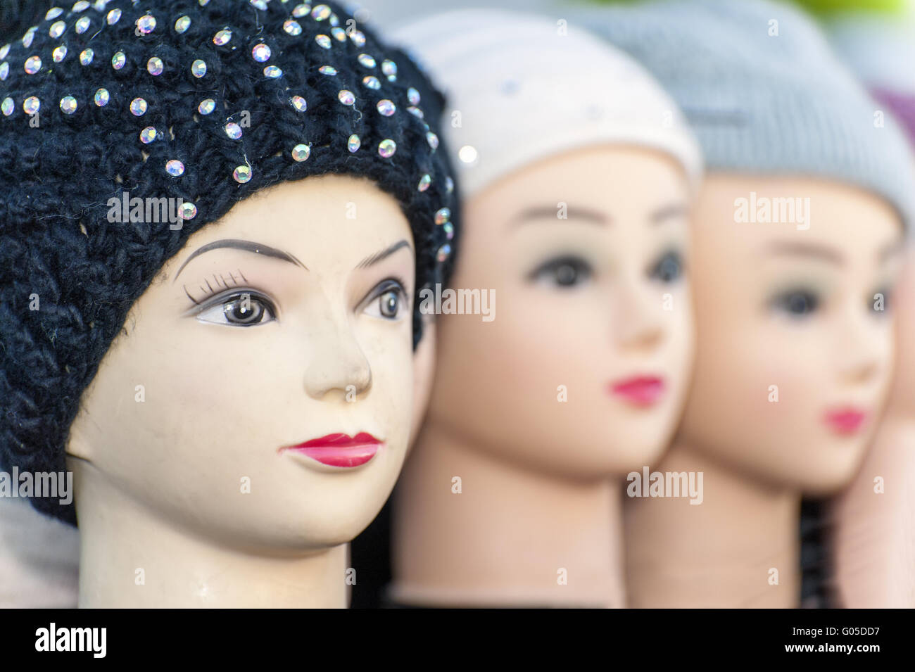 3 dolls heads side by side with knitted hats Stock Photo