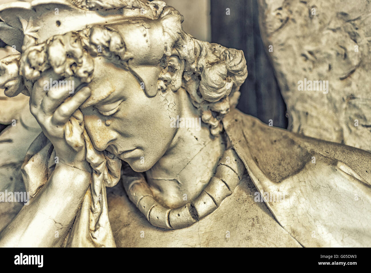 dusted statue of crying angel holding his head while tears is flowing ...