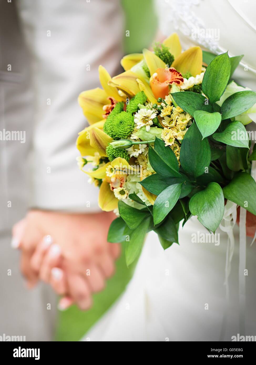 Detail of hands of wedding couple with wedding bouquet Stock Photo