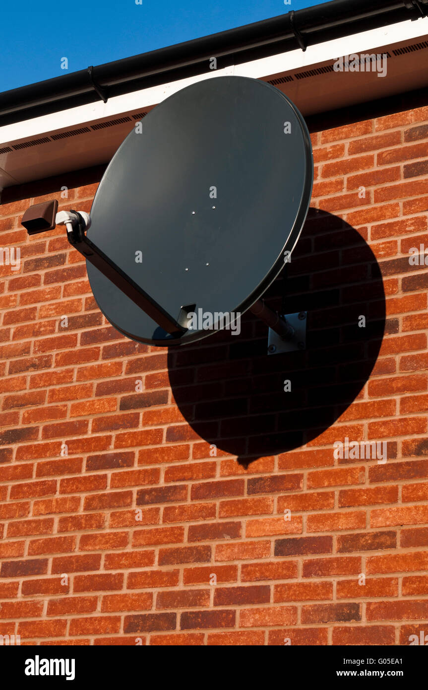black satellite dish attached to brick wall (residential house Stock