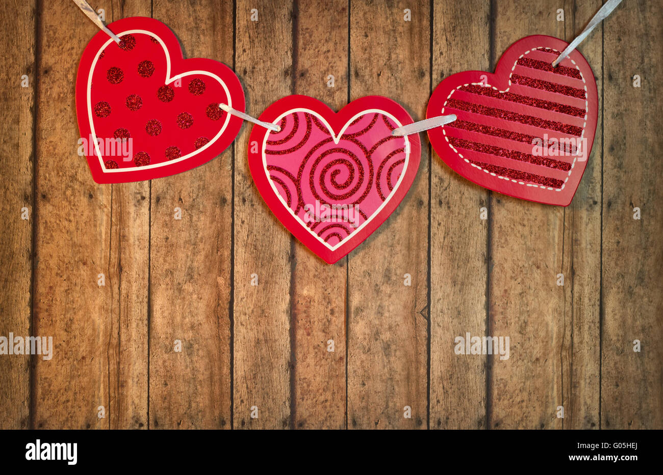 Red and Pink Valentine Hearts hanging from twine on a wood plank ...