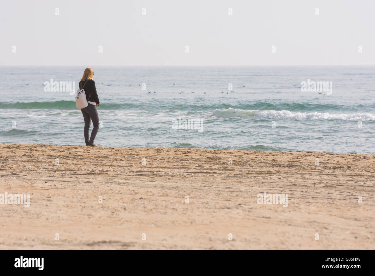 A young girl stands on the seashore and looks at the sea Stock Photo ...