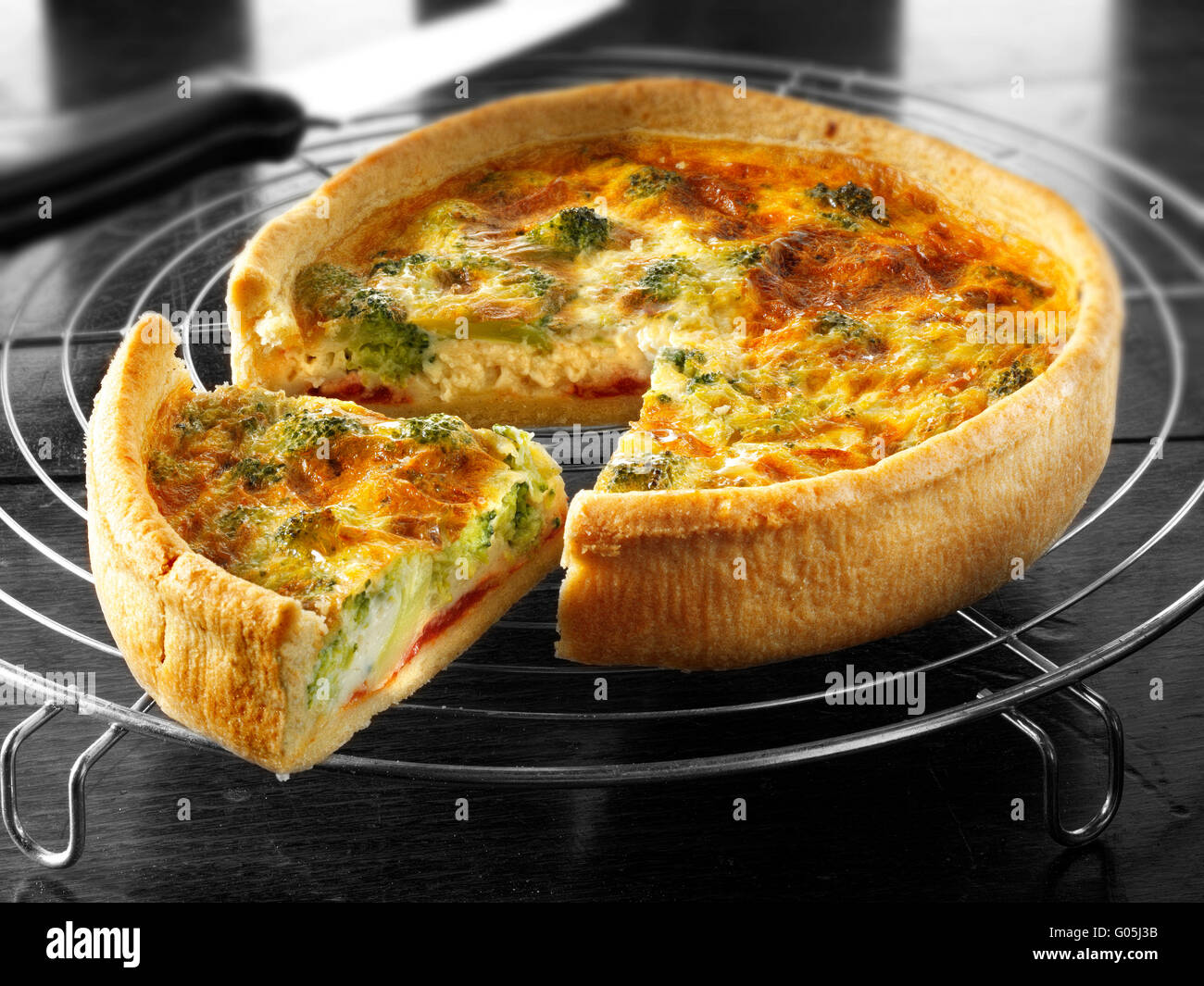 Whole cooked brocoli quiche with a slice out Stock Photo