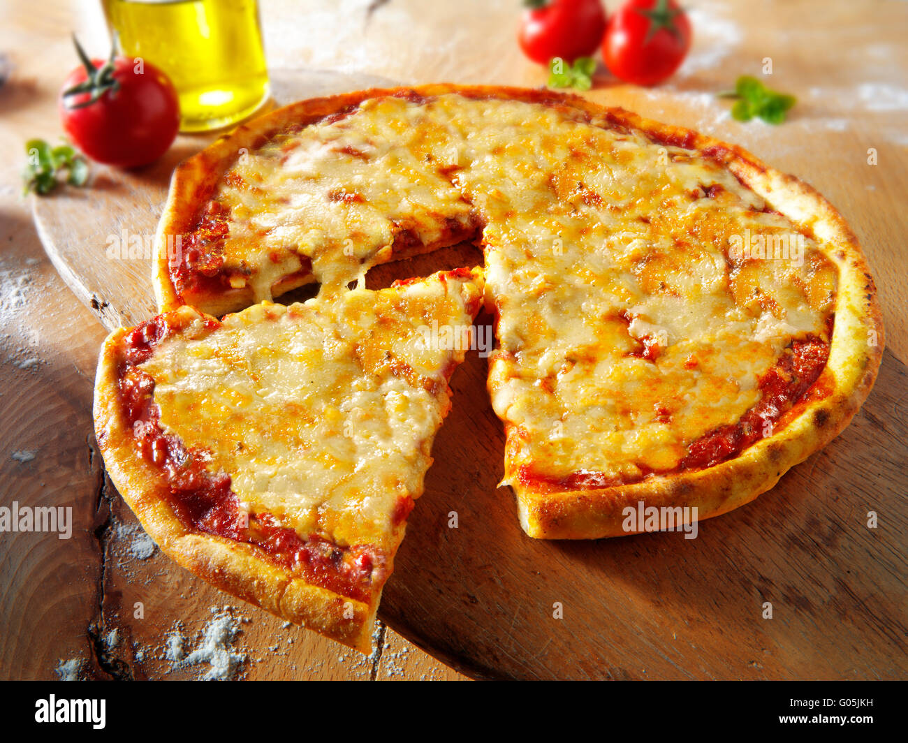 Cooked whole cheese and tomato Margherita pizza with a cut slice Stock Photo