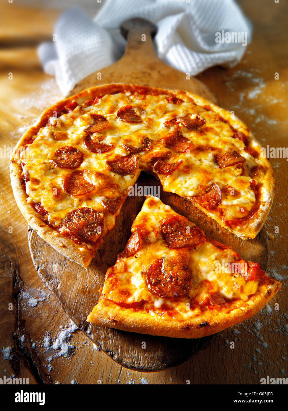 Cooked whole cheese and tomato pepperoni pizza with  a cut slice Stock Photo