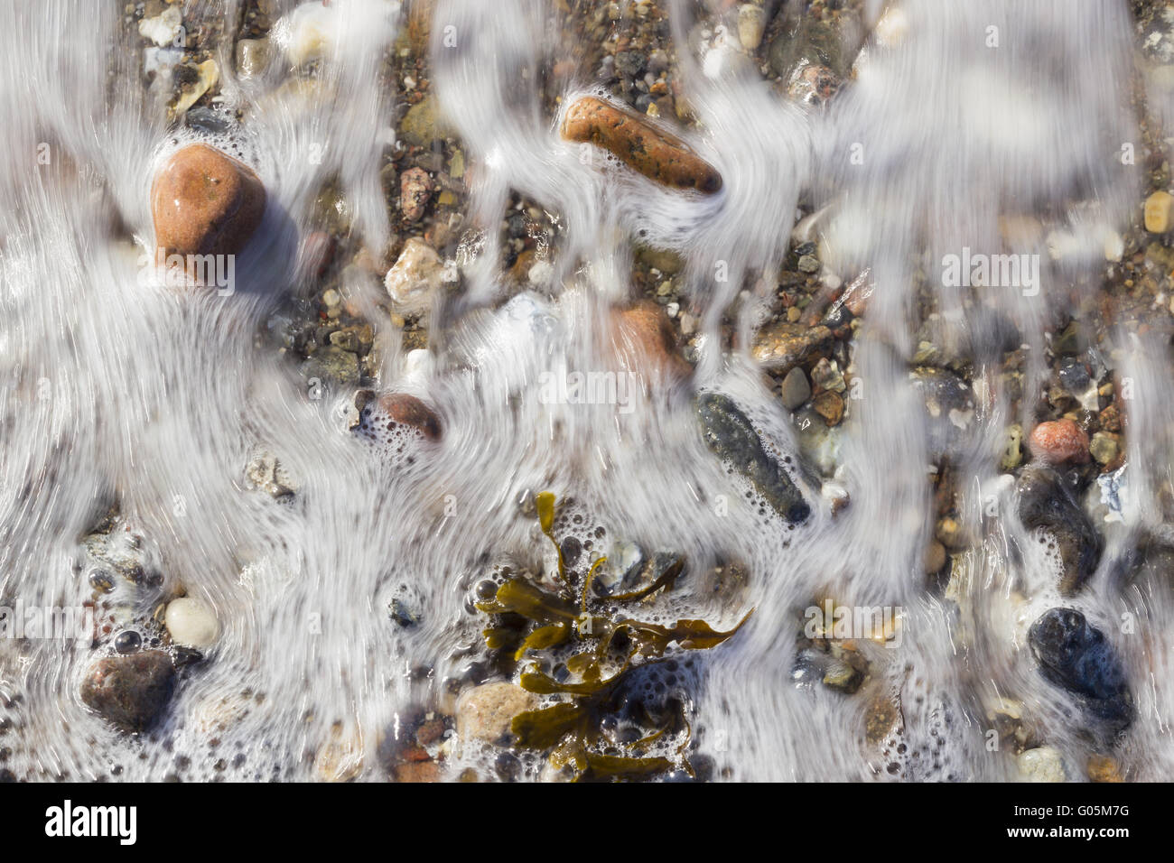 Flowing sea water at the beach pebbles on the shor Stock Photo