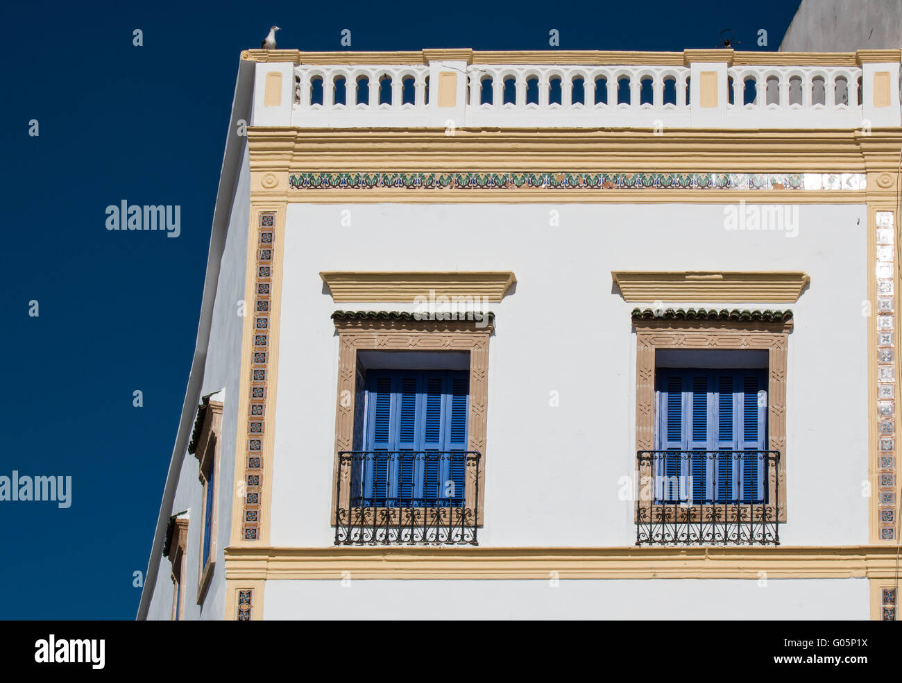 Enlightened corner of a house in Essaouira, Morocco. Matching blue color of the windows shutters and the sky. Stock Photo