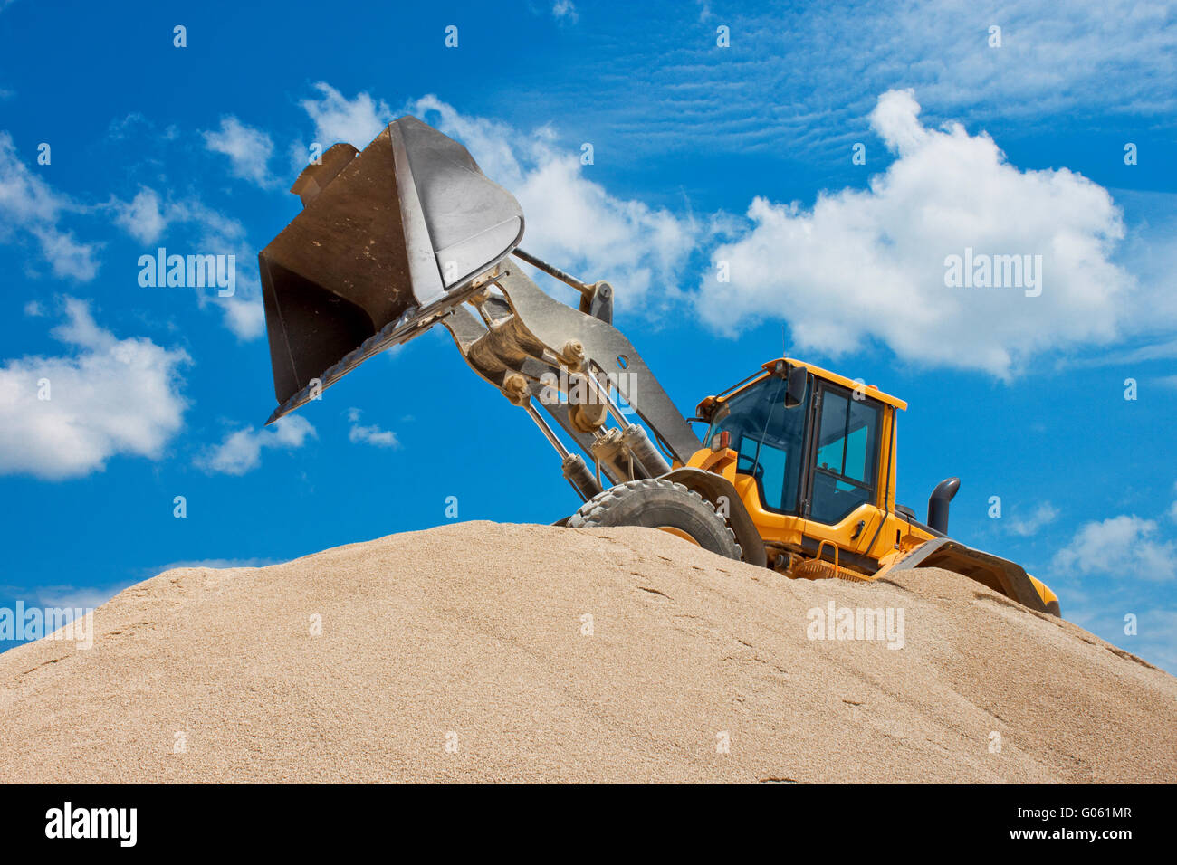 Yellow excavator on a construction site against blue sky Stock Photo ...