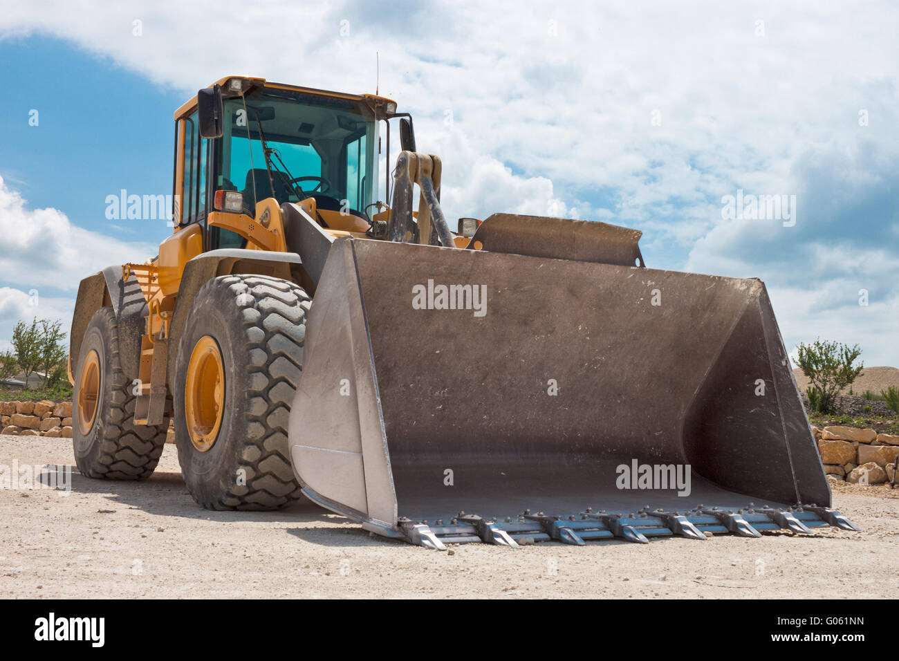 Yellow excavator on a construction site against blue sky Stock Photo ...