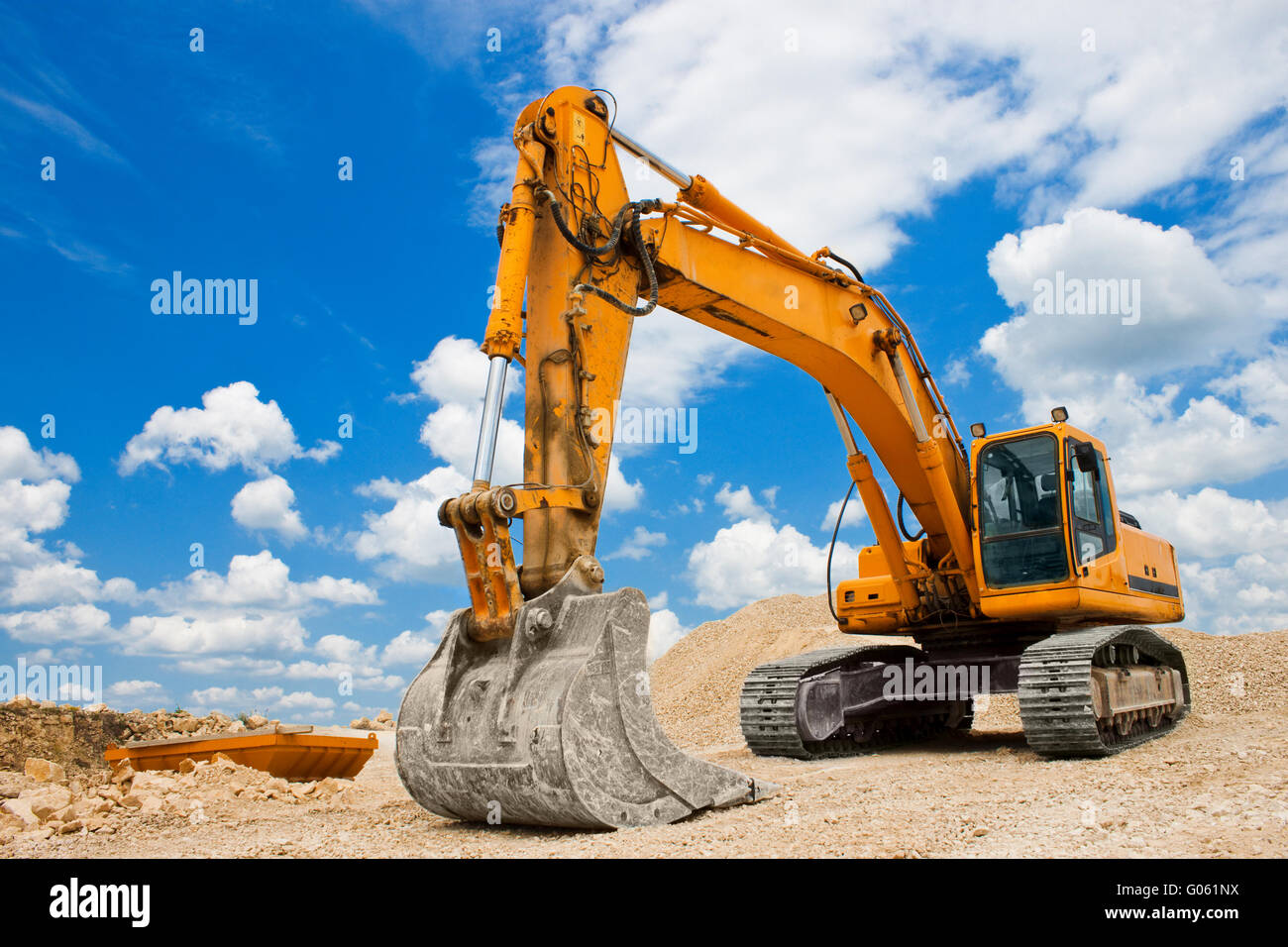 Yellow excavator on a construction site against blue sky Stock Photo ...