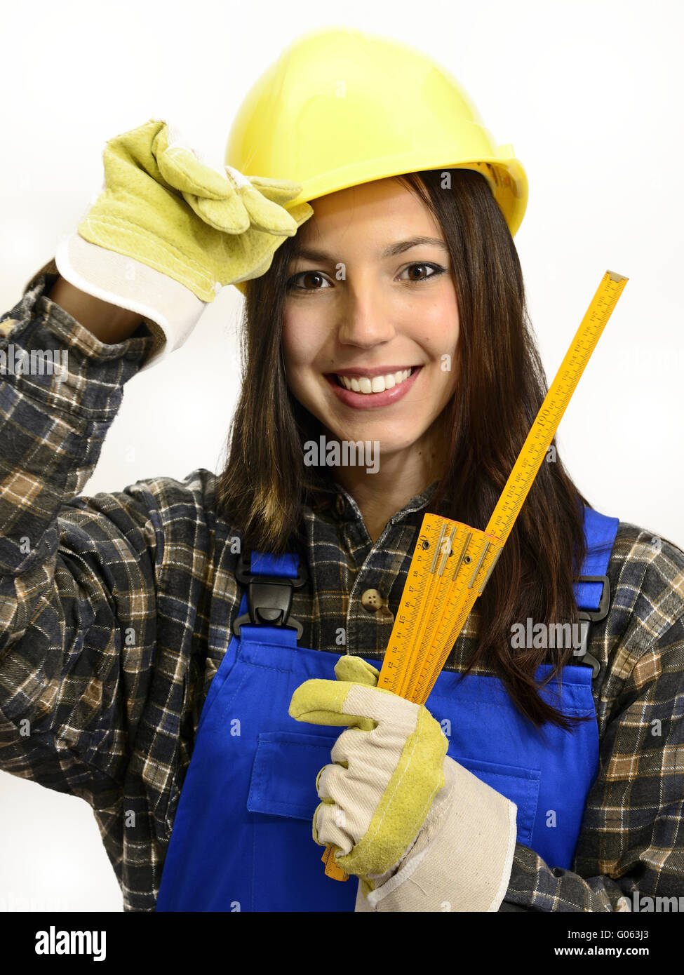 Young woman with helmet and work clothes holding a Stock Photo