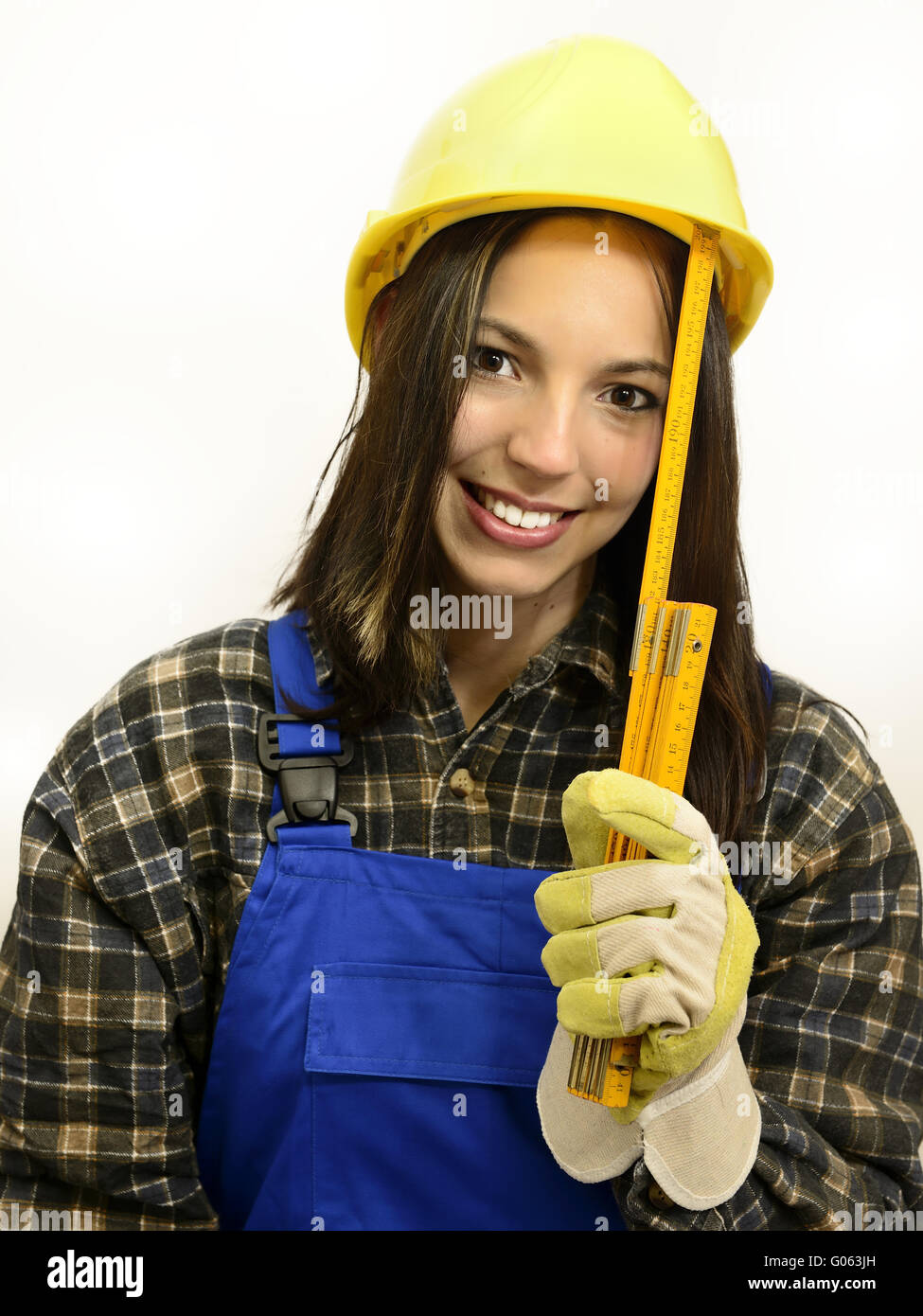 Young woman with helmet and work clothes holding a Stock Photo