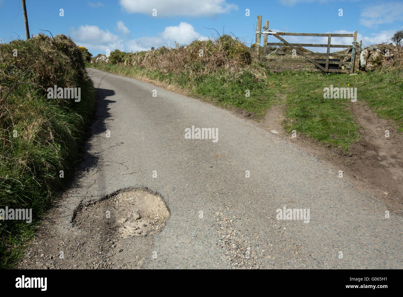 Countryside potholes in the road cause damage to cars and are a danger to unsuspecting motorcyclists and cyclists Stock Photo