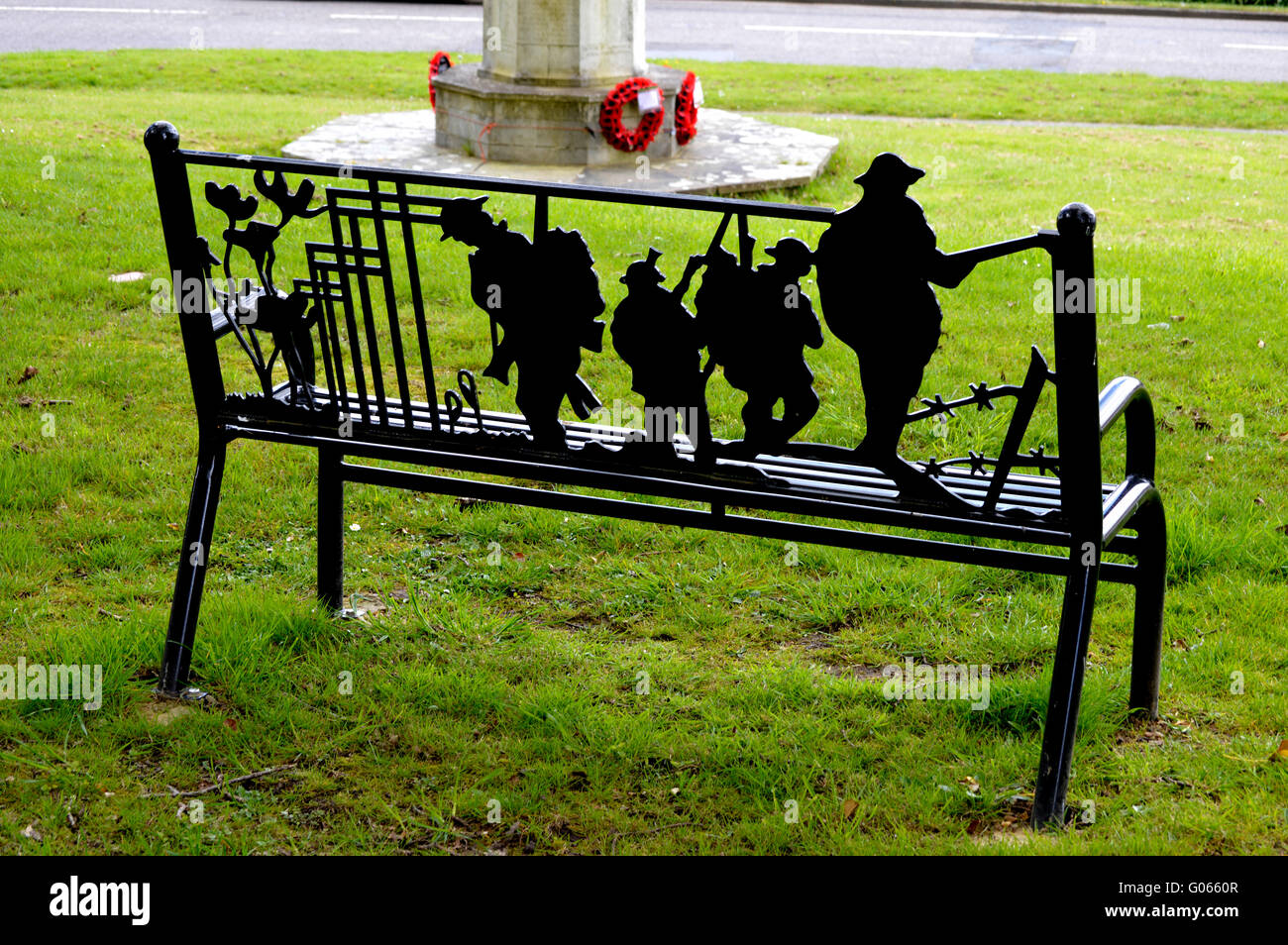 A War memorial bench in front of a war memorial. Stock Photo