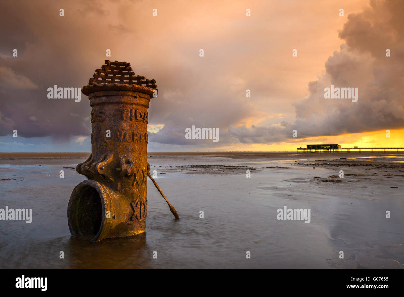 Colourful sunrise over the Irish Sea illuminating the 'Liverpool Fleetwood Victorian Cast Iron Tidal Standard at low water. The Roman numerals suggest it relates to a ship's draft marks in bygone times marking a channel for access to the now defunct and silted up port. Southport, Merseyside, Stock Photo