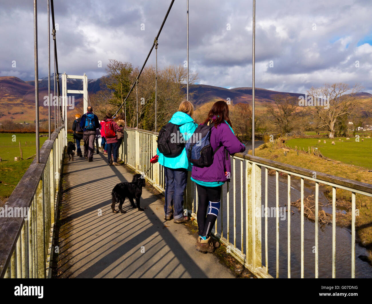 Dog walkers admiring scenery from a footbridge over the River Derwent