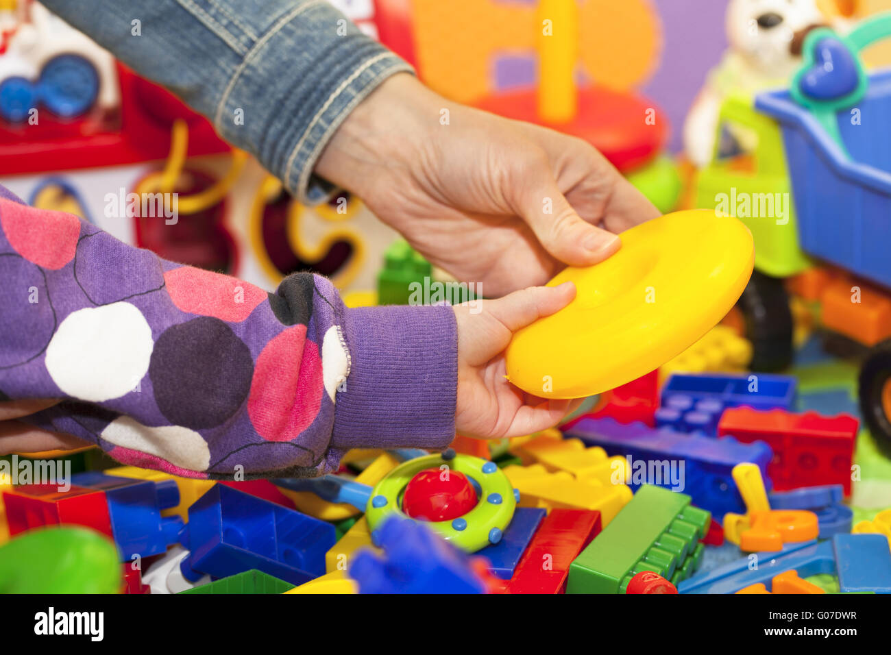 The mother and the child's arms at the toy pile Stock Photo
