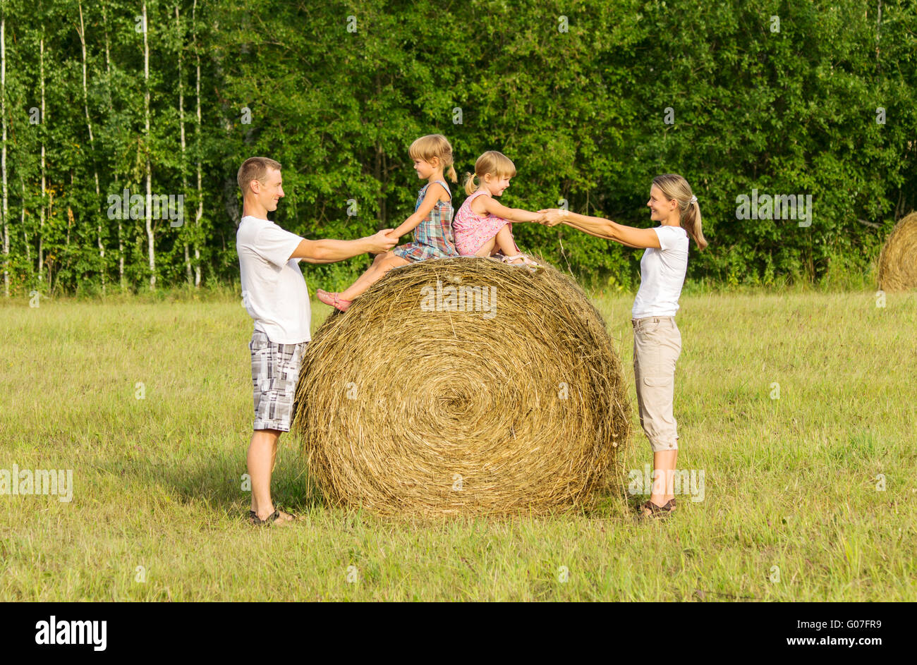 Happy family with child on haystack in sunny day Stock Photo