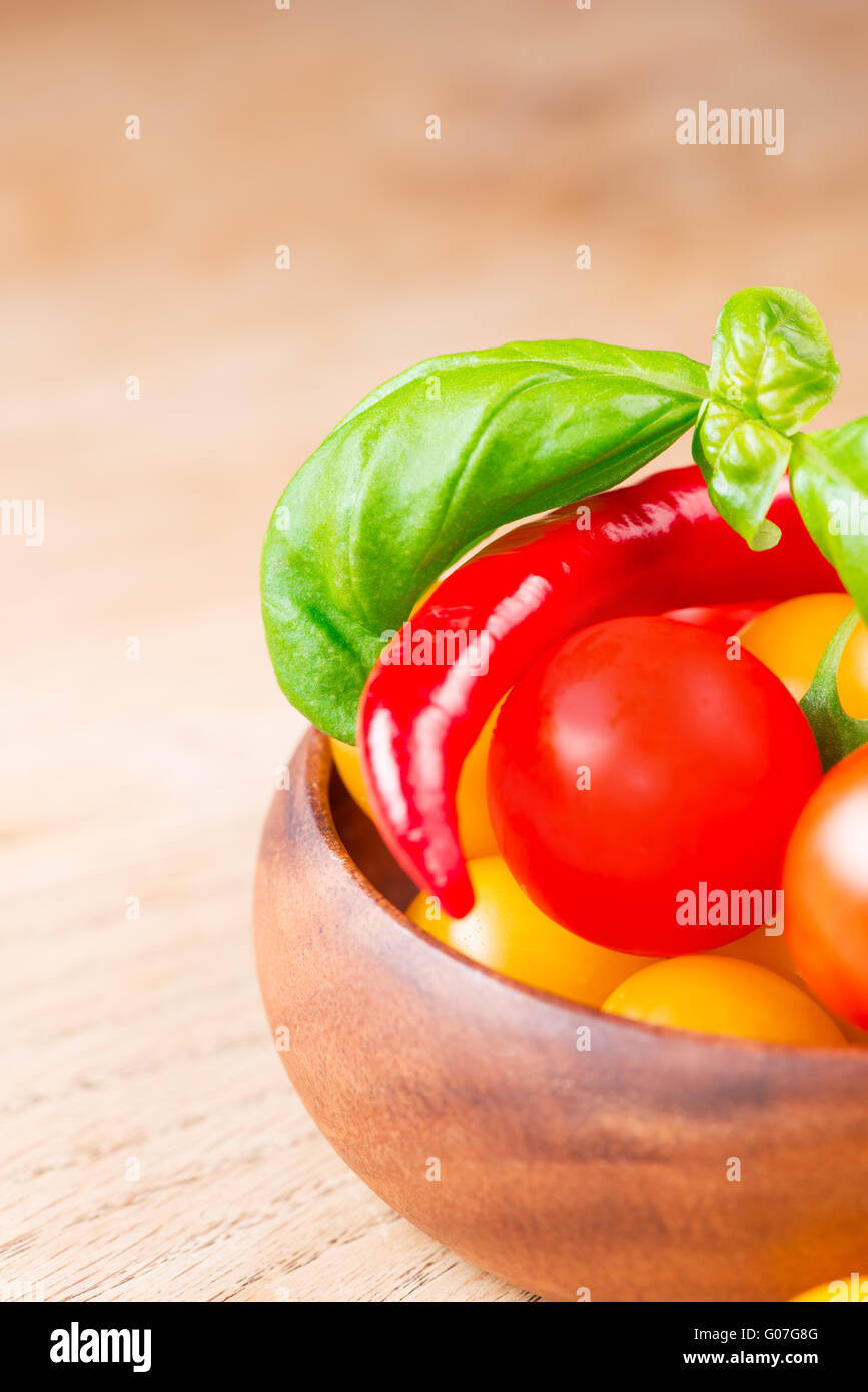 basil leafs with cherry tomatoes and chili pepper in wooden bowl Stock Photo
