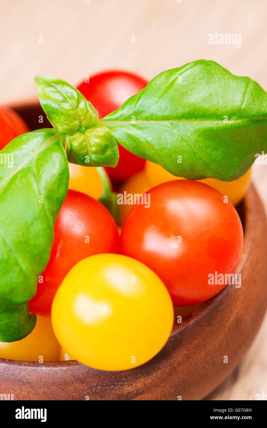 basil leafs with cherry tomatoes in wooden bowl close up Stock Photo