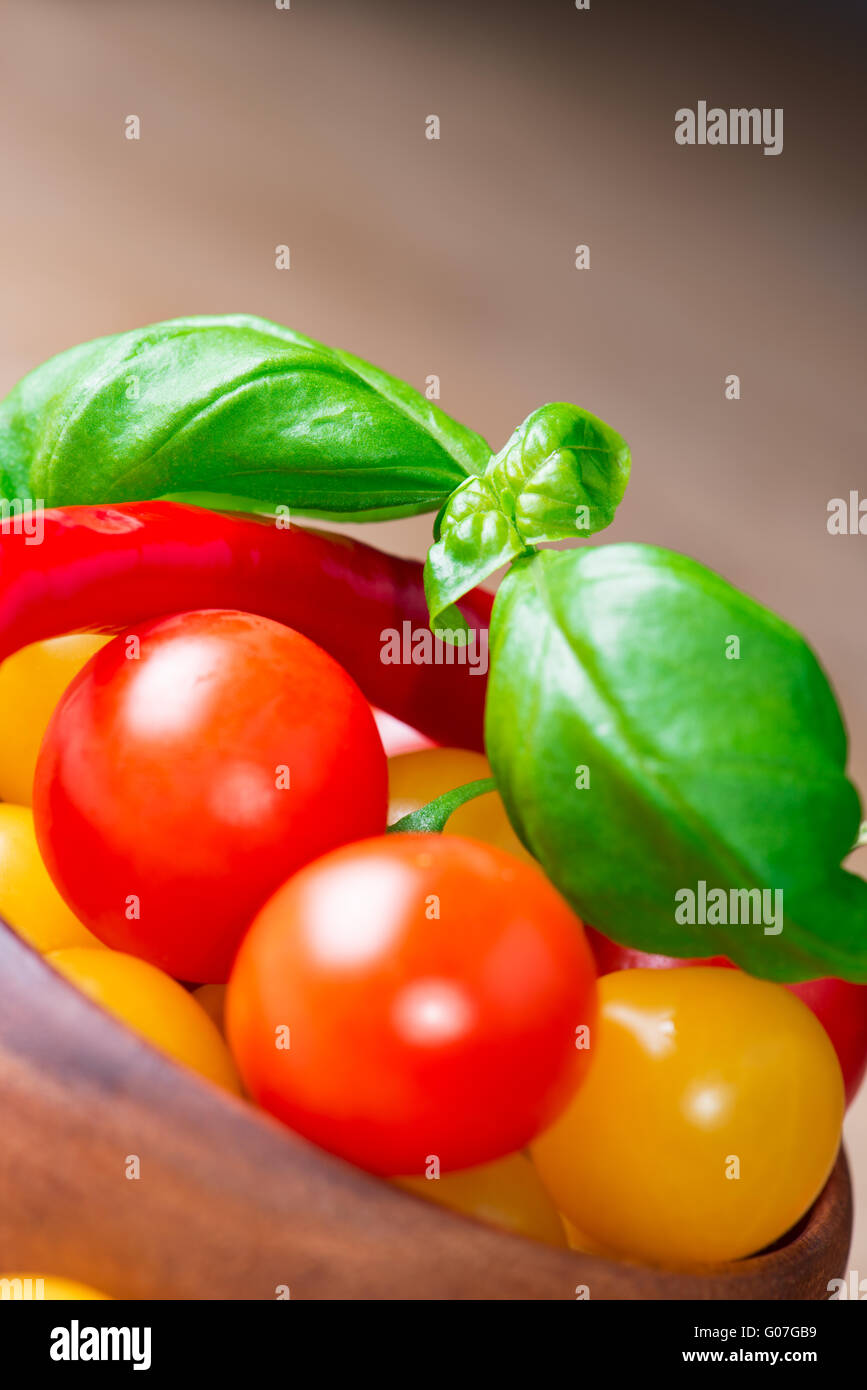 basil leafs with tomatoes and pepper in wooden bowl Stock Photo
